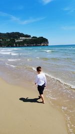 Full length of boy on beach against sky