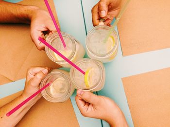 Cropped image of friends holding lemonade jars at table