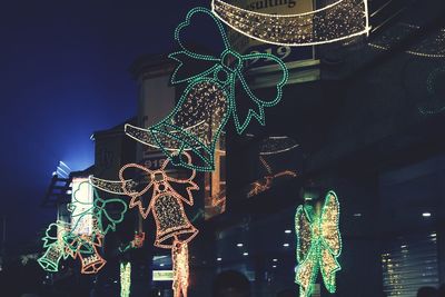 Low angle view of illuminated christmas decorations in city at night