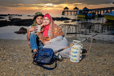 Full length of couple sitting at seashore