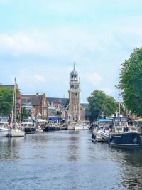 Sailboats in river by buildings in city against sky