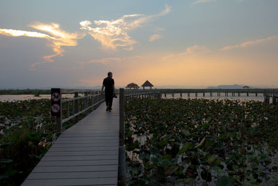 Man standing on bridge against sky during sunset