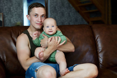 Portrait of cute baby boy lying on sofa at home