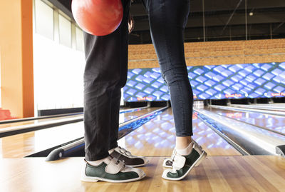 Woman standing on tiptoe with friend at bowling alley