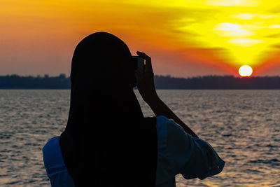 Rear view of woman on beach during sunset