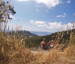 Women sitting on cliff gazing upon city