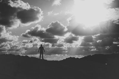 Full length of man standing on mountain against cloudy sky