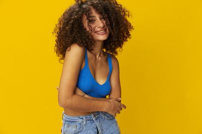 Portrait of young woman against yellow background