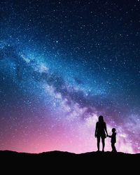 Silhouette father and son against sky at night