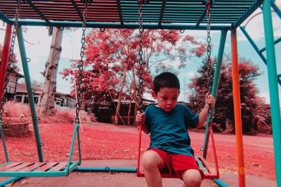 Boy playing on swing in playground
