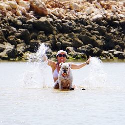 Woman with dog splashing water in sea