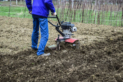 Low section of man using lawn mower on field