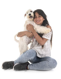 Portrait of smiling woman with dog sitting against white background