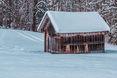 Wooden hut in a forest with snow covered trees in the alps