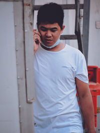 Young man looking away while standing on door