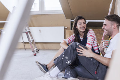 Happy young couple sitting and taking coffee break at home