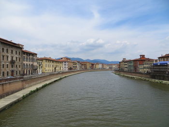 Bridge over river amidst buildings in city against sky