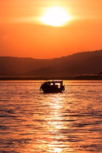 Silhouette boat in sea against orange sky