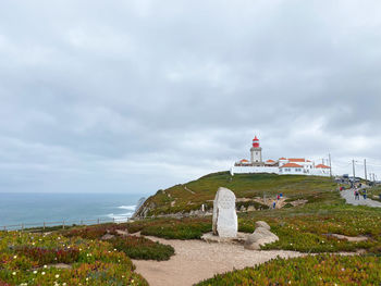 Lighthouse by the ocean against sky