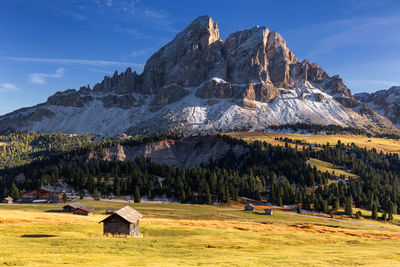 House on field by mountain against sky