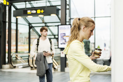 Woman using atm at railroad station