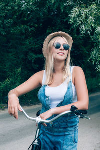Teenage girl looking away while standing with bicycle on road
