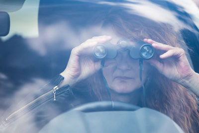 Close-up of woman looking through binoculars while sitting in car