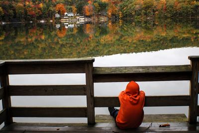 Rear view of man sitting on bench in lake