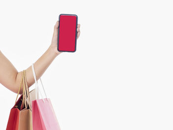 Midsection of woman using mobile phone against white background