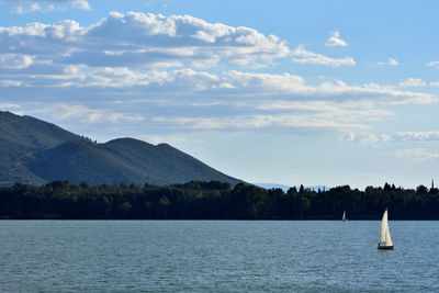 Scenic view of sea by mountains against sky