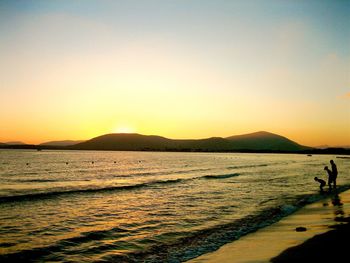 Silhouette man on beach against clear sky during sunset