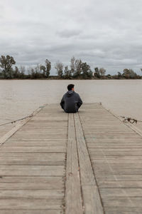 Rear view of man sitting on pier