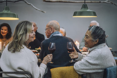 Senior women with wineglasses talking to each other at dinner party