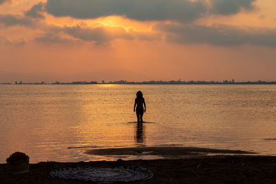 Silhouette man standing on beach against sky during sunset