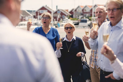 Male and female friends cheering while toasting champagne flutes outdoors