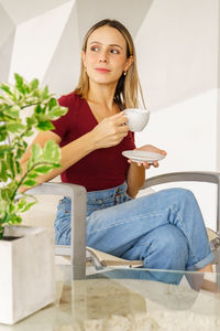 Young woman using mobile phone while sitting on sofa at home