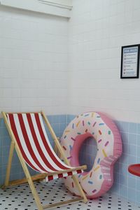 View of chair with pool raft against wall at bathroom