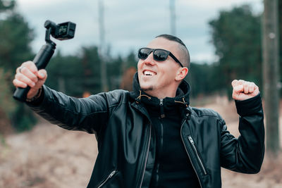 Young man wearing sunglasses filming with video camera