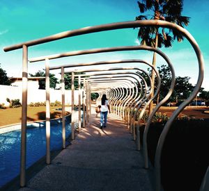 Rear view of woman walking at park sky