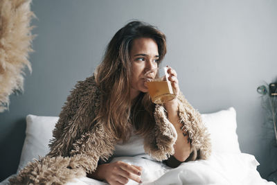 Young woman looking away while sitting at home