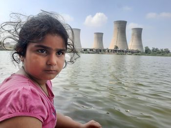 Portrait of young woman standing against river