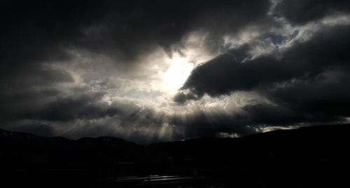 Low angle view of sunlight streaming through clouds