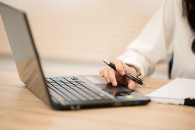 Midsection of businesswoman using laptop in office