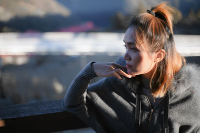 Young woman using mobile phone while sitting outdoors