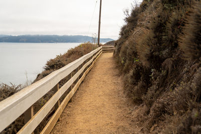 Empty road by sea against sky