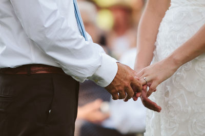 Midsection of bridegroom holding bride hand during wedding ceremony