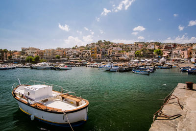 Boats moored on canal by houses against sky