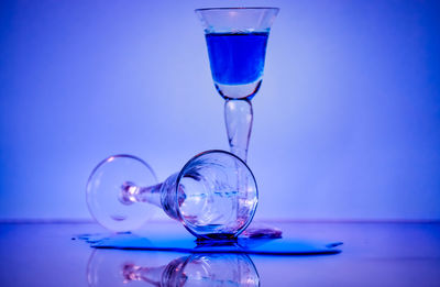 Close-up of water glass on table against blue background