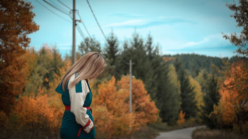 Woman standing by trees against sky