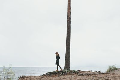 Woman standing by sea against clear sky